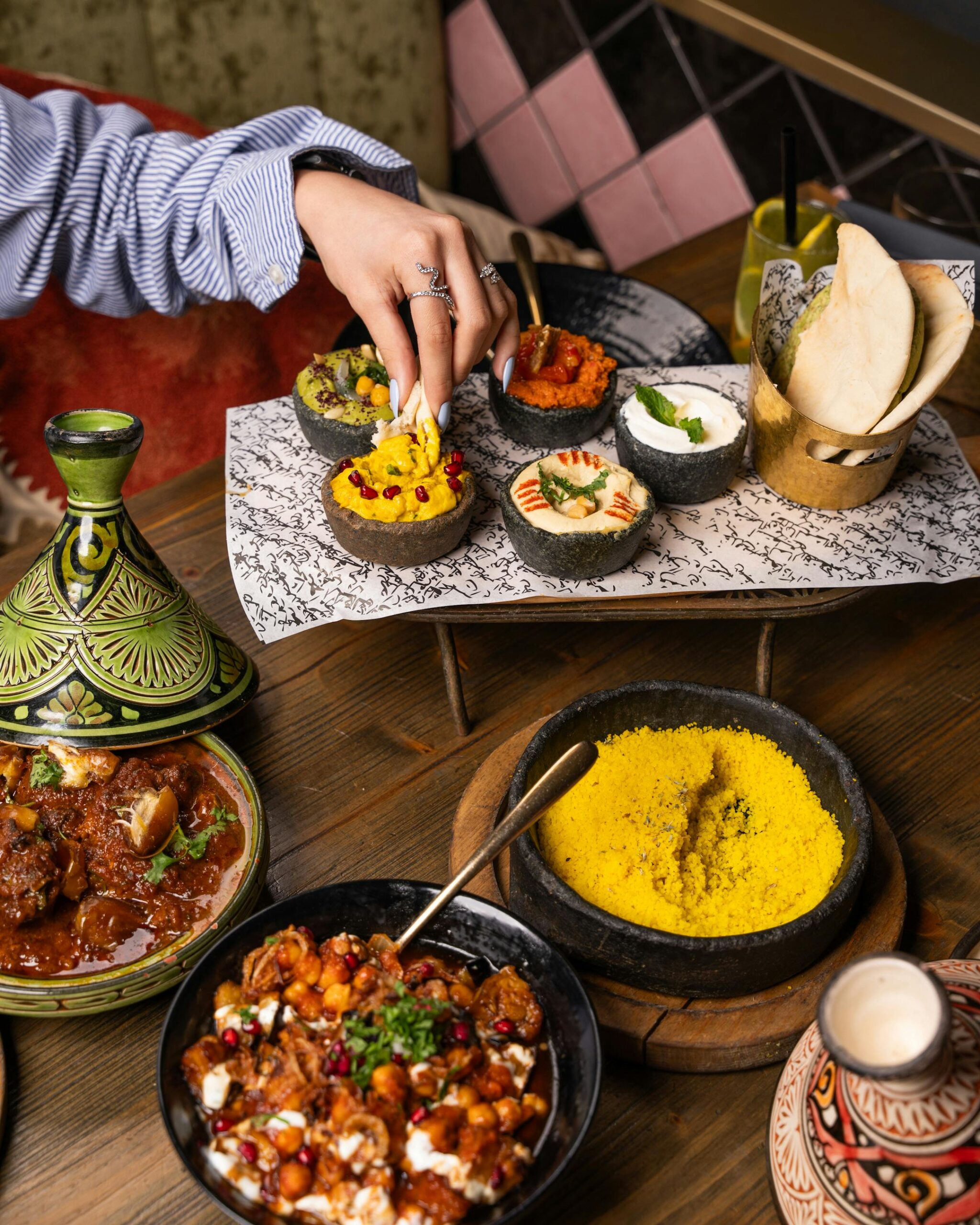 A vibrant Moroccan meal featuring beef tagine, various dips, bread, and yellow couscous, perfect for a cultural culinary experience.