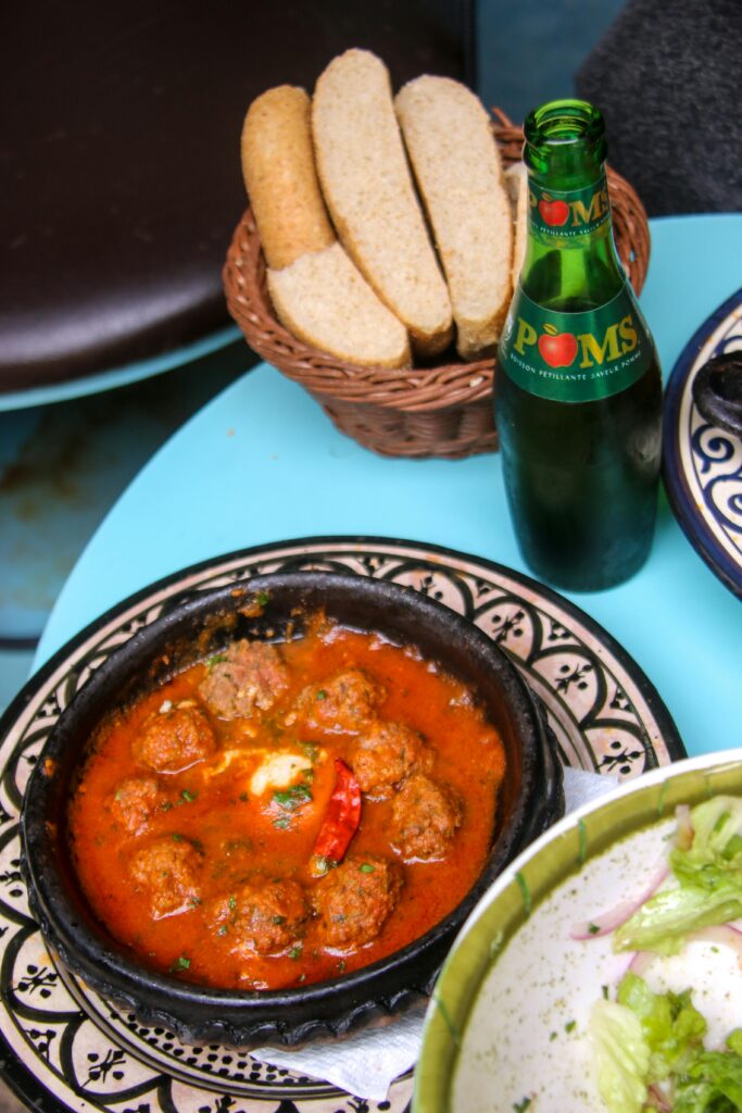Delicious Moroccan meatballs in rich tomato sauce with bread and local drink.